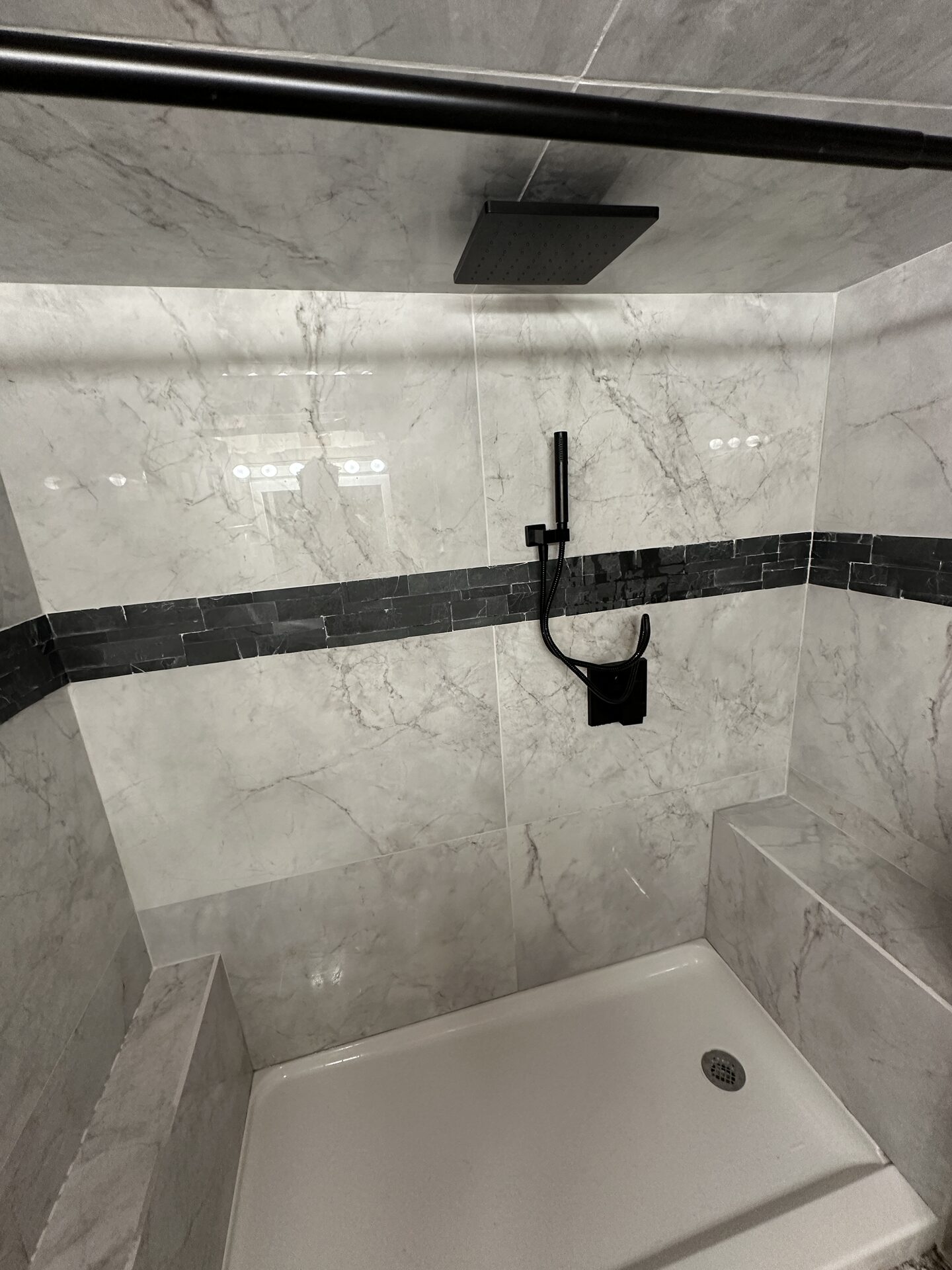 Marble tile shower detail with grab bar and black fixtures